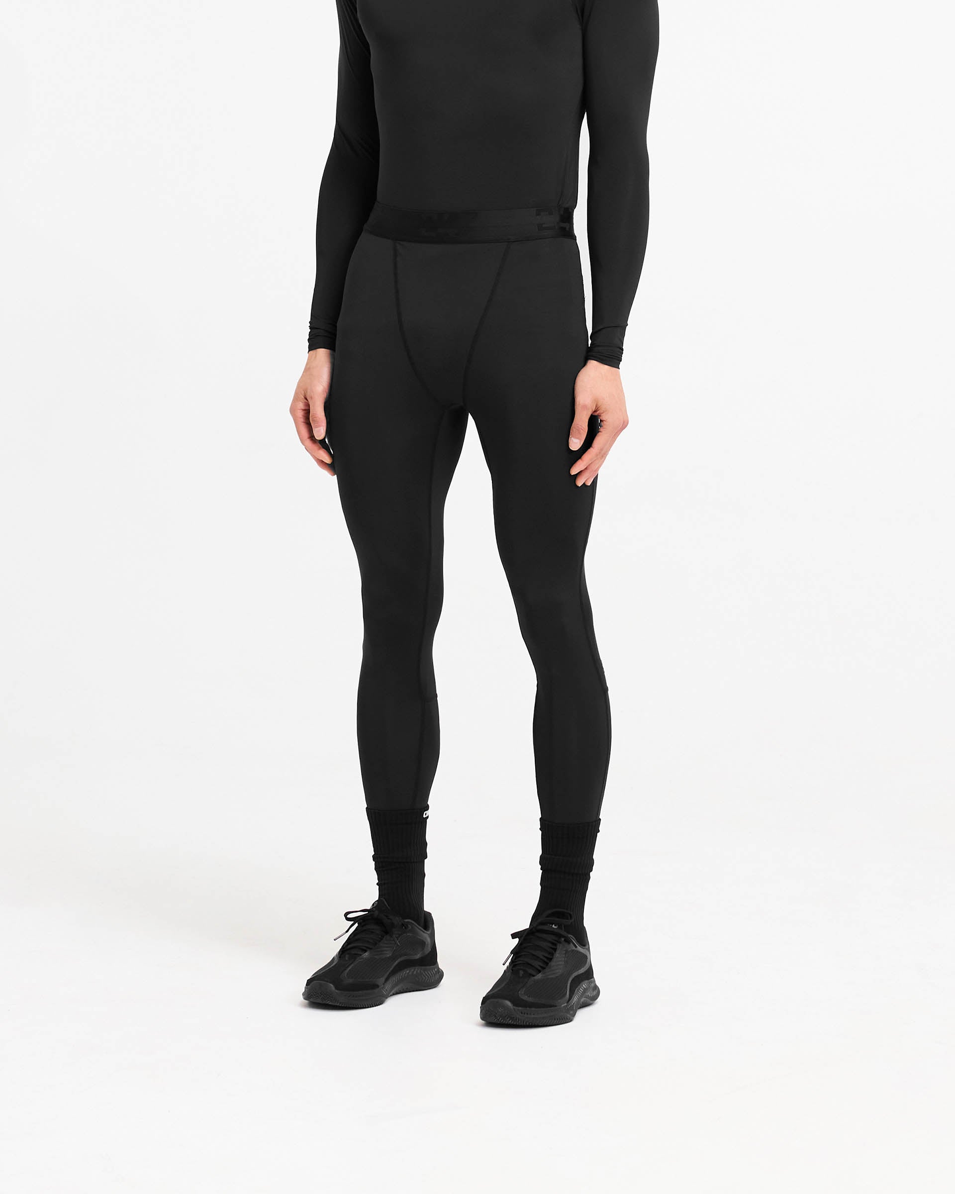 Man wearing black leggings on a plain white background | 247 Compound Legging in Black | Full length leggings with branded waistband | 247 Pants | Represent Clo